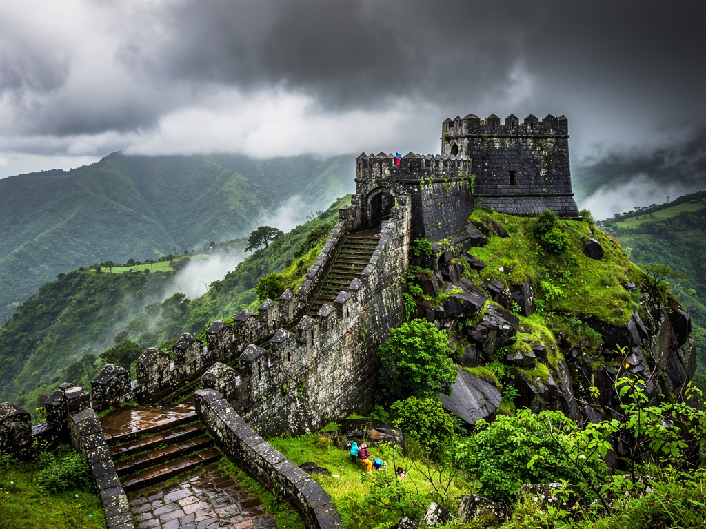 Stone fortifications of Lohagad Fort on a ridge above green Sahyadri hills