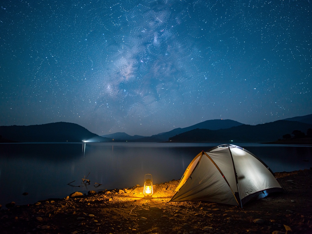 A starlit night sky over a tent at a Pawna Lake campsite
